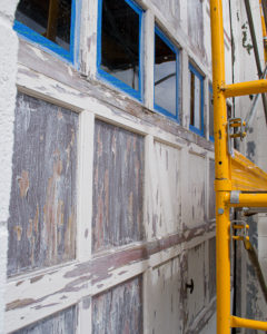 Garage door on Third Street in Marquette at the beginning of the mural project. Pictured here are some of the challenges with the project: peeling paint and wood veneer.