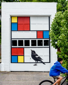 Mid-progress of mural project. Marquette artist Taryn Okesson takes a photograph of the mural progress after scaffolding is removed. Mondrian Garage Mural Third Street, Marquette, MI.